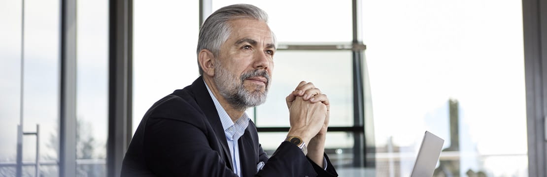 Man sitting in front of his laptop looking off in thought.