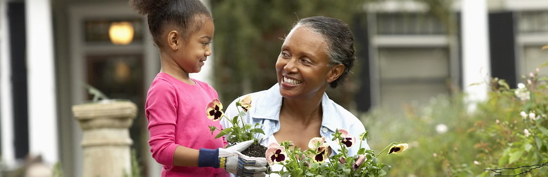 A woman and her granddaughter plant flowers in their garden